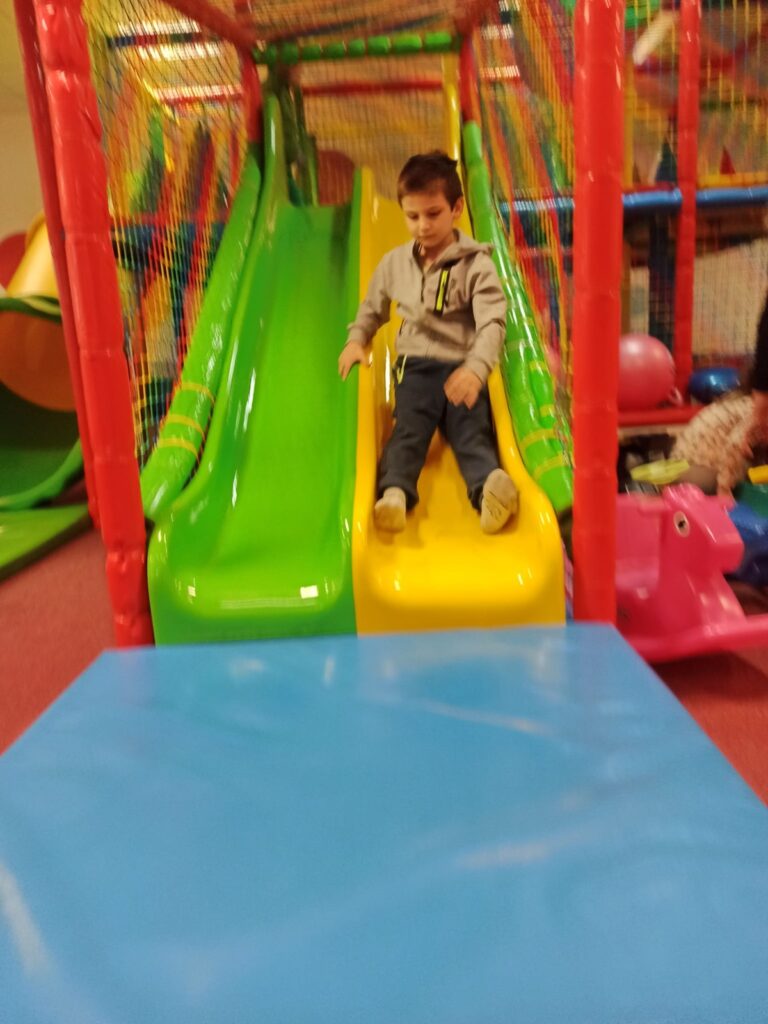 Chłopiec zjeżdża ze zjeżdżalni w klubie dla dzieci