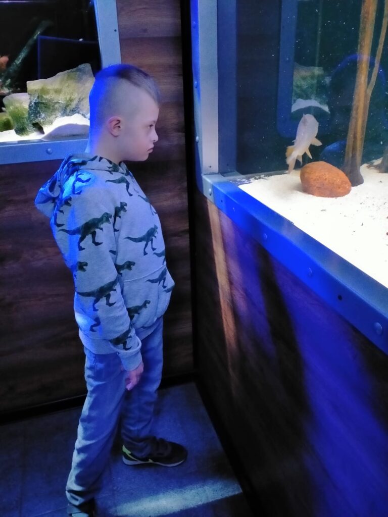 Chłopiec w oceanarium patrzy na rybę w akwarium.